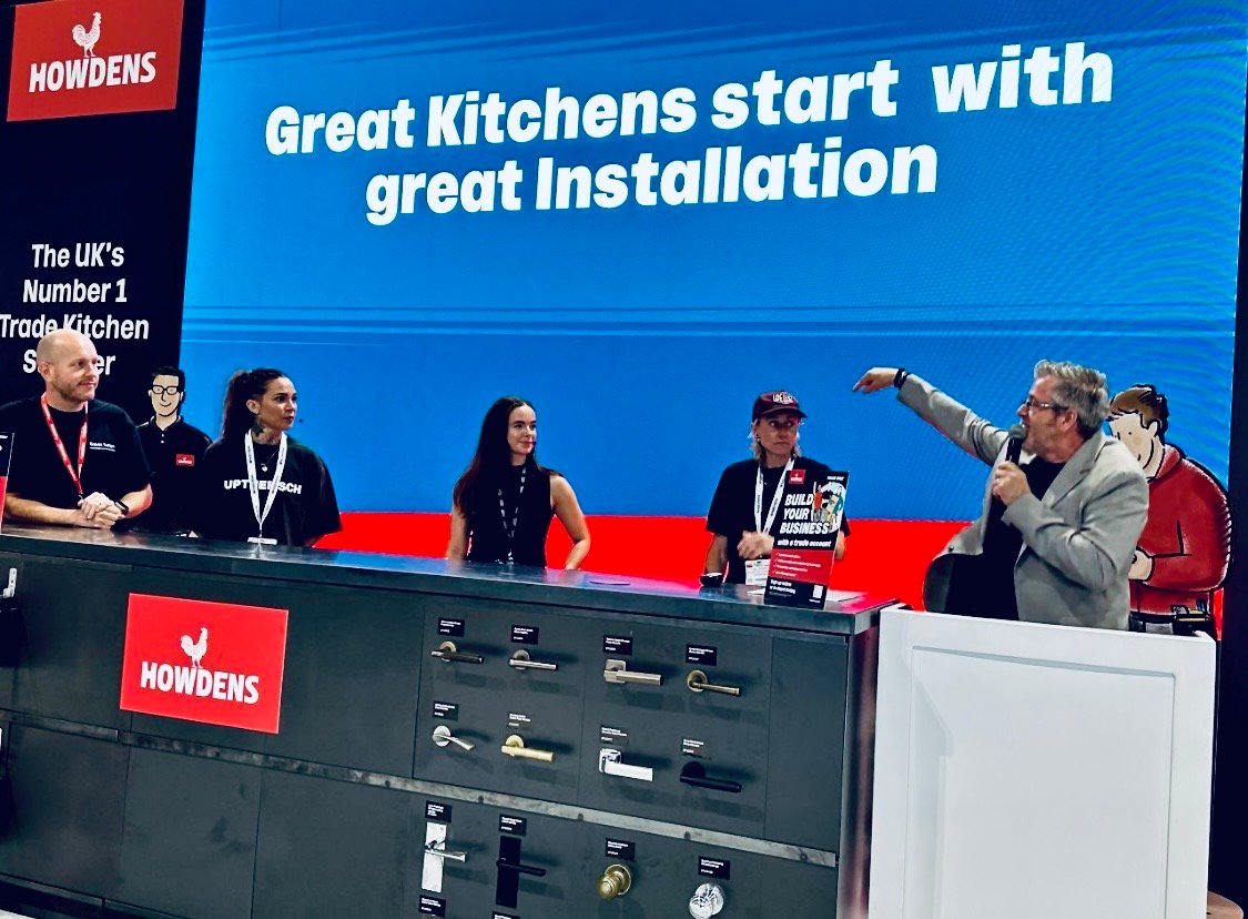 Mark Conacher chairing an industry panel with a microphone on the Howdens stage at InstallerSHOW